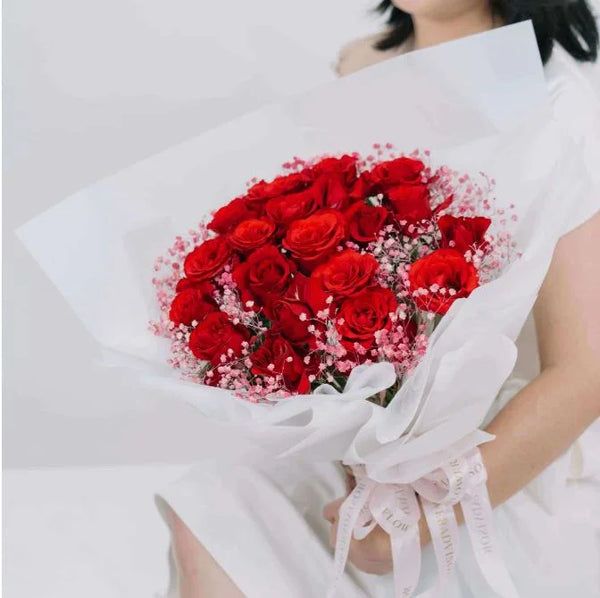 Red rose bouquet with pink baby's breath wrapped in white paper for flower delivery