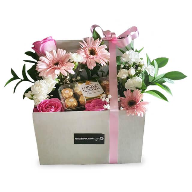 Flower delivery box with pink gerberas, roses, white blooms, greenery, and chocolates.
