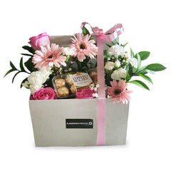 Flower delivery box with pink gerberas, roses, white blooms, greenery, and chocolates.