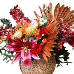 Exotic flower arrangement with red lilies, roses, and dried palm leaves for flower delivery