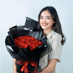 Smiling woman holding luxury bouquet of 36 red roses for flower delivery