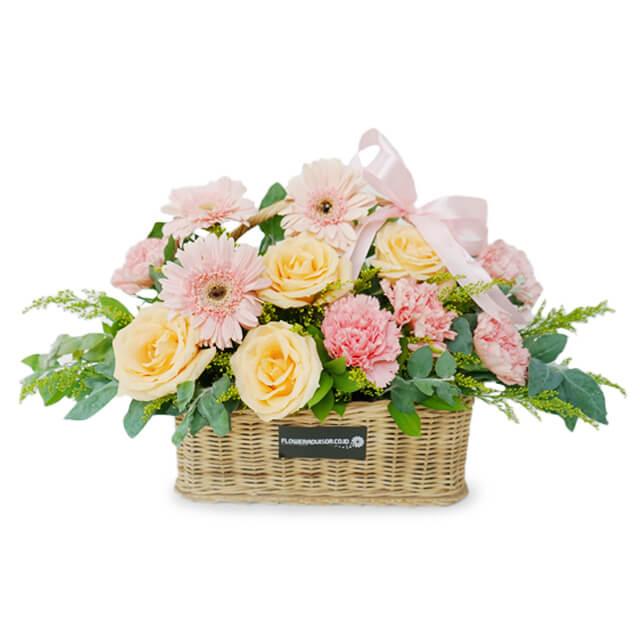 Flower delivery basket with pink gerberas, yellow roses, green foliage and a pink ribbon.