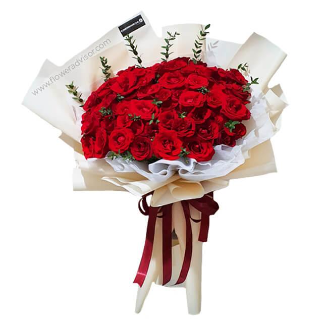Elegant round bouquet of 60 red roses with greenery for flower delivery in Singapore