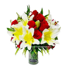 Fresh flower delivery of red roses and yellow lilies in a clear glass vase arrangement