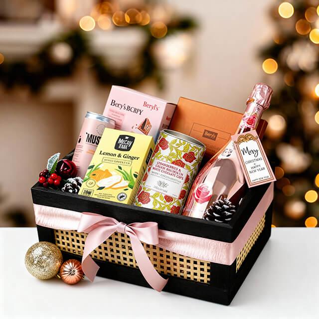 Festive gift basket with pink sparkling wine, assorted snacks and flowers, ideal for flower delivery.