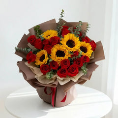 Flower delivery of fresh sunflower and red rose bouquet wrapped in brown paper