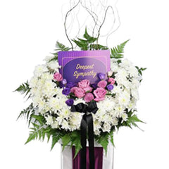 Sympathy flower arrangement with white chrysanthemums, purple roses, and a condolence card for delivery