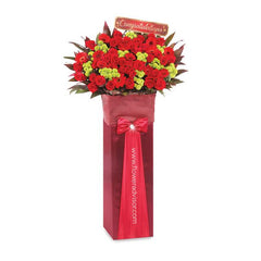Standing flower arrangement with red roses and greenery, perfect for congratulatory flower delivery.