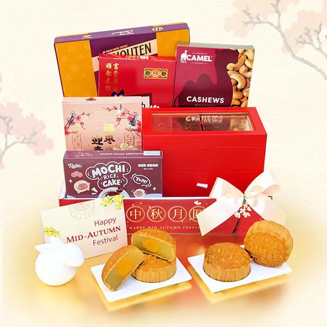 A mid-autumn festival gift hamper featuring an assortment of Chinese snacks and treats, including mochi cakes, cashew nuts, and traditional sweets, arranged in and around red gift boxes with a white bow. Several treats are displayed on small white plates in front, set against a soft beige background with a faint cherry blossom motif.
