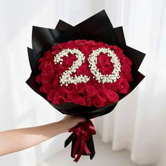 Hand holding a bouquet of red roses with '20' in white flowers for flower delivery