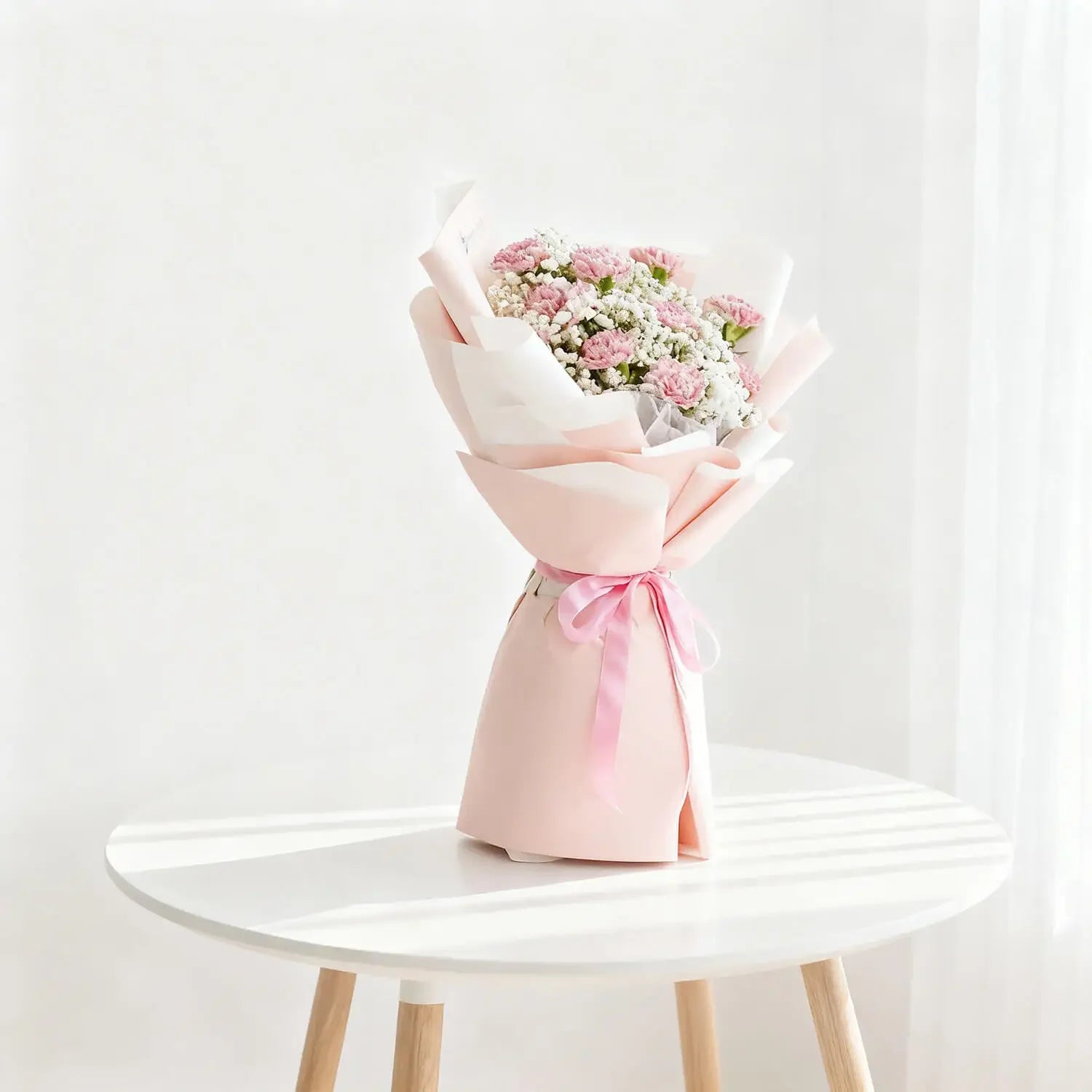 Pink and white flower bouquet for delivery, wrapped with ribbon on round table