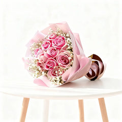 Pink rose bouquet with baby’s breath in gift wrap on table, perfect for flower delivery.