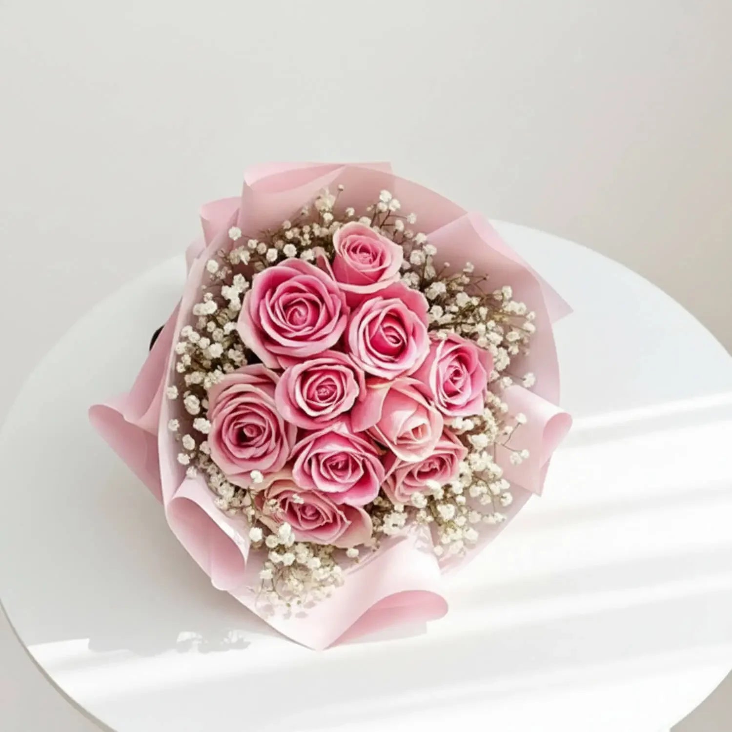 Pink rose bouquet with baby’s breath for flower delivery, arranged on white table