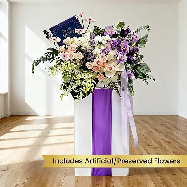 Grand flower delivery arrangement with roses, orchids, and sympathy card in a white box.