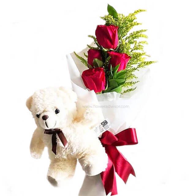 Hand holding flower delivery of red rose bouquet with greenery and plush teddy bear