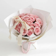 Elegant bouquet of pink roses with white wrapping and ribbon, perfect for flower delivery.