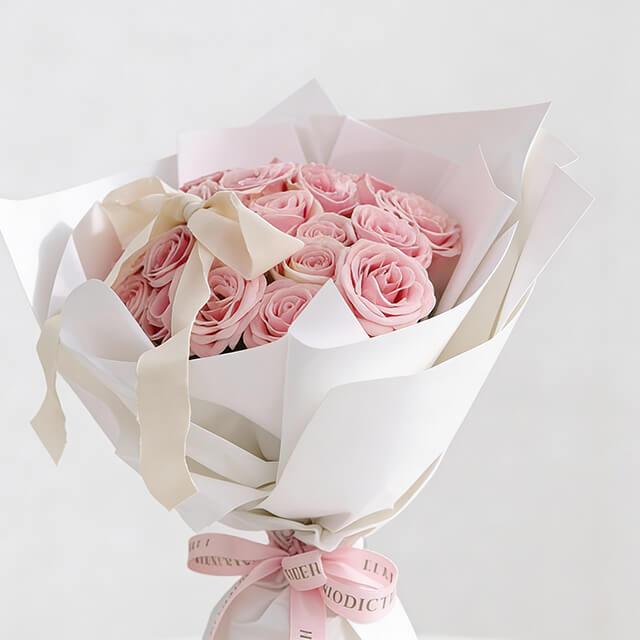 Elegant pink rose bouquet with white wrapping and ribbon, perfect for flower delivery