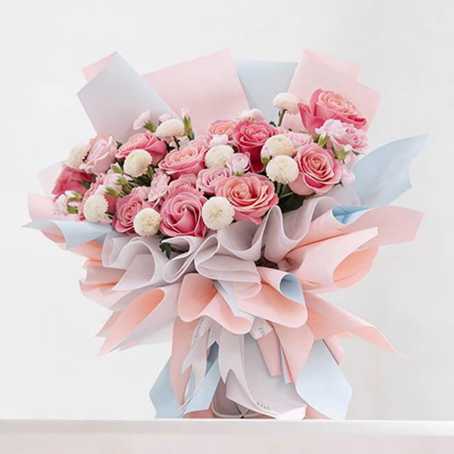Elegant pink rose and white pompom bouquet for flower delivery, wrapped in pastel paper