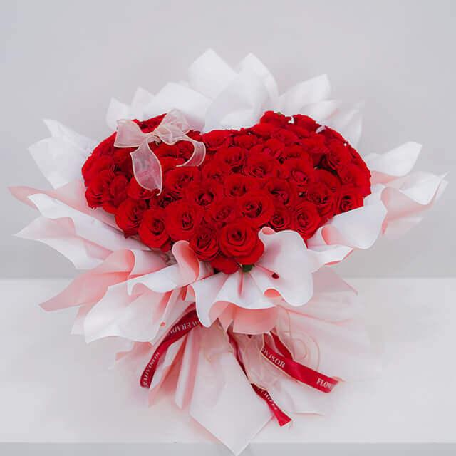 Heart-shaped red rose bouquet wrapped in pink paper for flower delivery