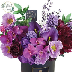 Vibrant purple and pink faux flower arrangement in a black box for flower delivery