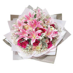 Flower delivery bouquet with pink lilies and hot pink roses, arranged in pastel wrapping.