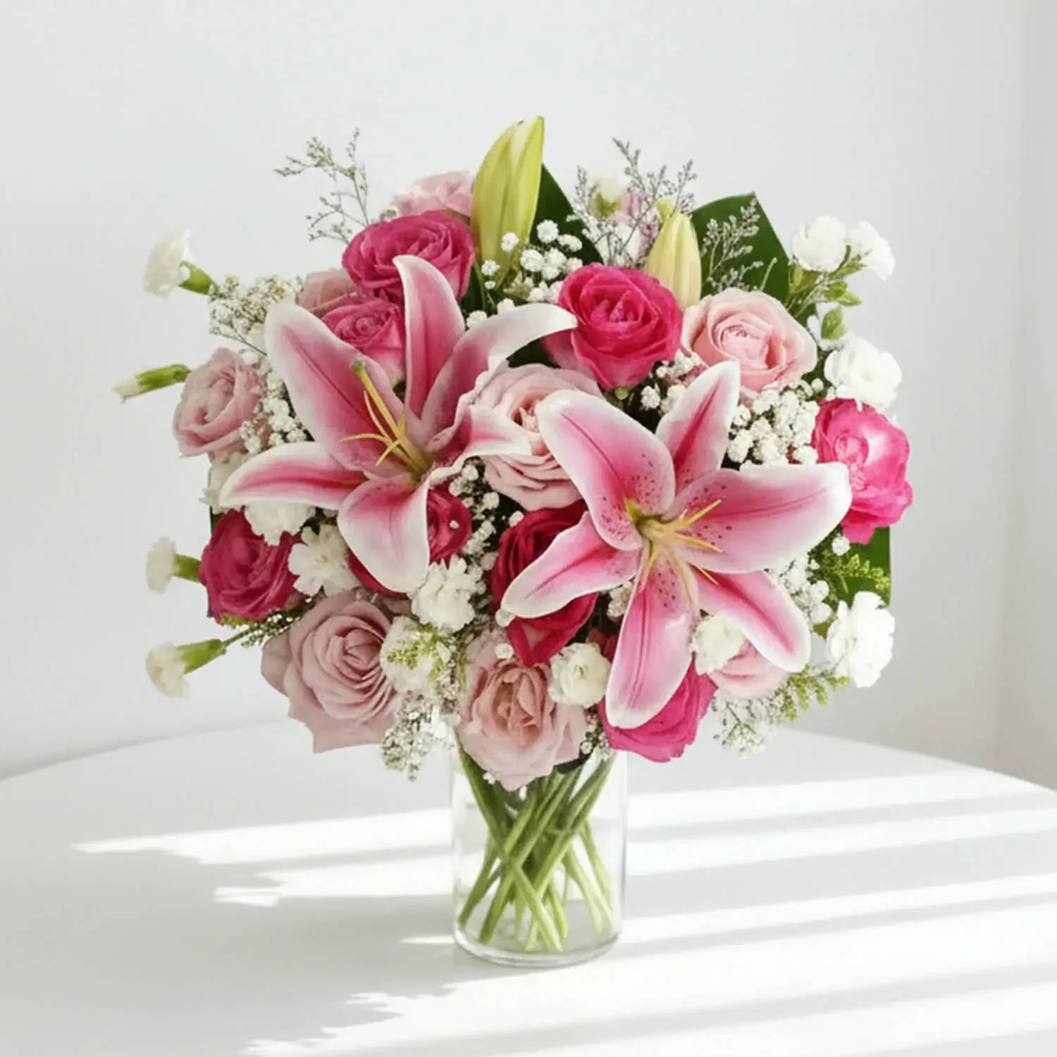 Elegant pink lilies and roses bouquet in glass vase for flower delivery
