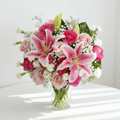 Elegant pink lilies and roses bouquet in glass vase for flower delivery
