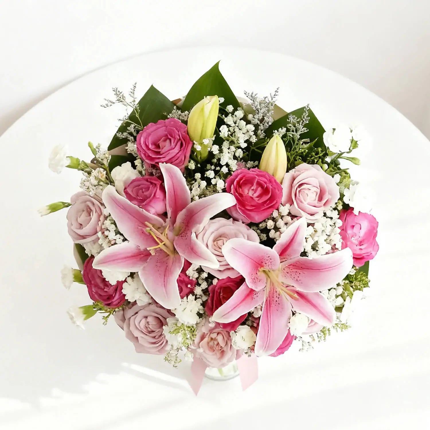 Pink lilies and roses bouquet in a vase for flower delivery, top view
