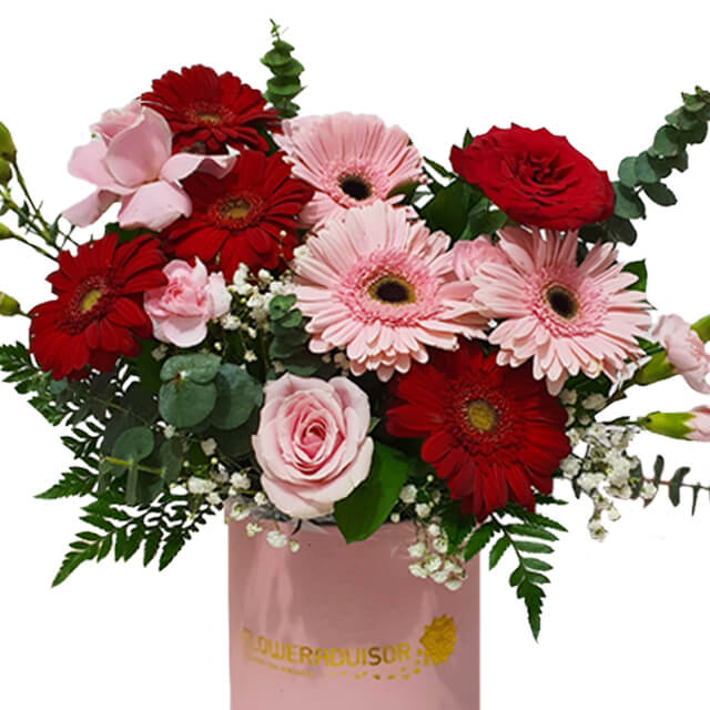 Fresh flower arrangement with pink and red gerberas and roses in a box for delivery