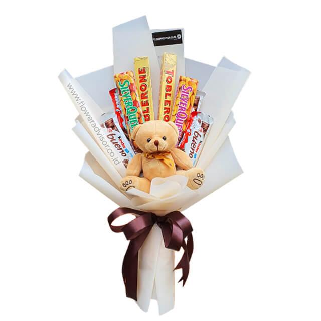 Candy bouquet with teddy bear for flower delivery, wrapped in white paper with chocolate bars