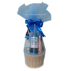 Flower delivery hamper with red wine, chocolates, and gourmet treats in a wicker basket