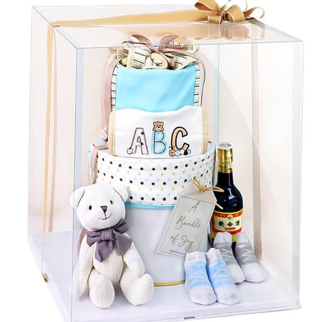 Baby gift hamper with plush bear, baby clothes, socks, and bottle, ideal for flower delivery