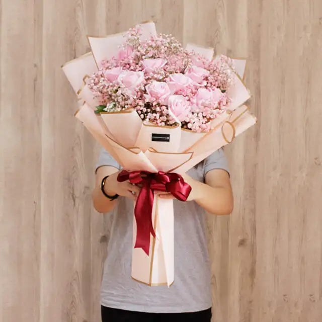Hand holding large pink rose bouquet with baby's breath for flower delivery