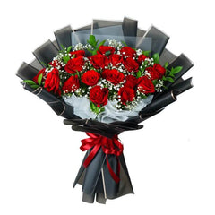 Elegant flower delivery bouquet with fresh red roses, baby's breath, and greenery in black wrapping.