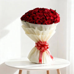 Elegant bouquet of red roses with white wrapping and red ribbon, perfect for flower delivery.