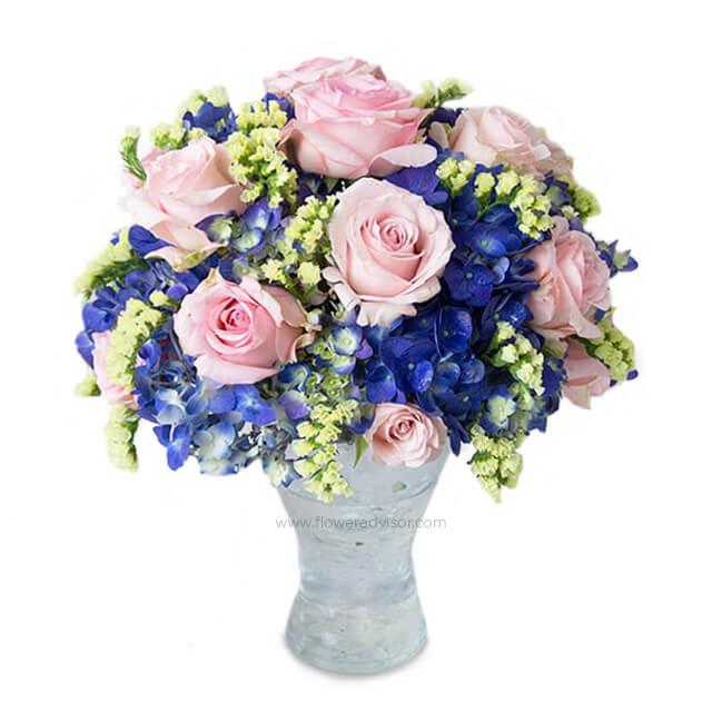 Mixed flower bouquet with pink roses and blue hydrangeas in a vase for flower delivery