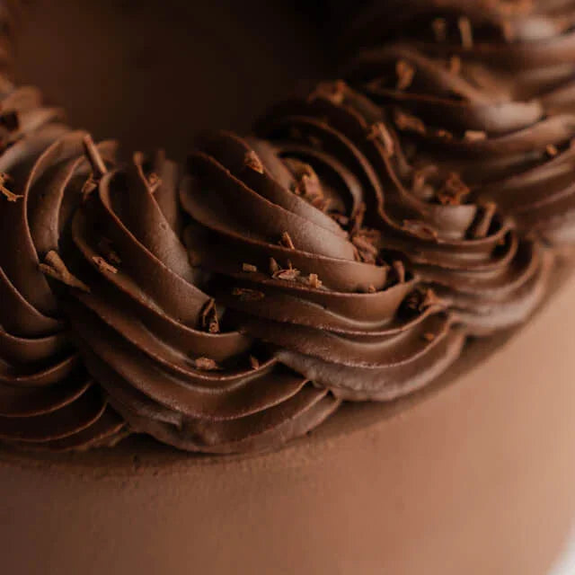 Close-up of chocolate cake decorated with swirl icing, ideal for cake and flower delivery