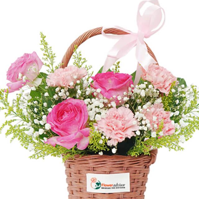 Flower delivery basket with pink roses, carnations, baby’s breath and greenery