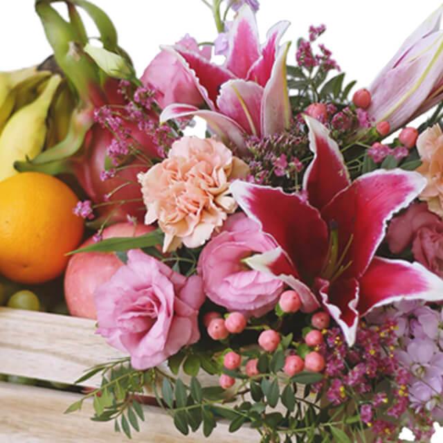 Fresh flower delivery crate with lilies, carnations, and assorted fruits