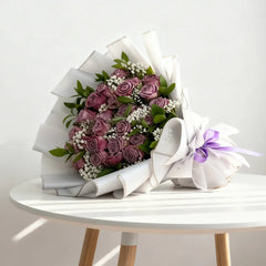 Elegant mauve rose bouquet with greenery, white filler flowers and purple ribbon for flower delivery