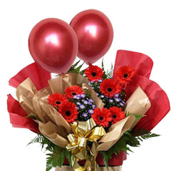 Festive flower arrangement with red gerberas, purple accents, gold ribbon and balloons for delivery