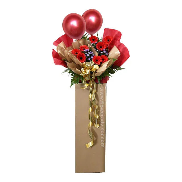 Flower delivery of red gerbera daisy arrangement with balloons and decorative ribbon