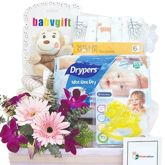 Baby gift hamper with plush toy, diapers, muslin washcloths, teether, and fresh flowers for delivery