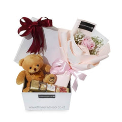 Flower delivery gift set with small pink bouquet, teddy bear, and chocolates in a white box.