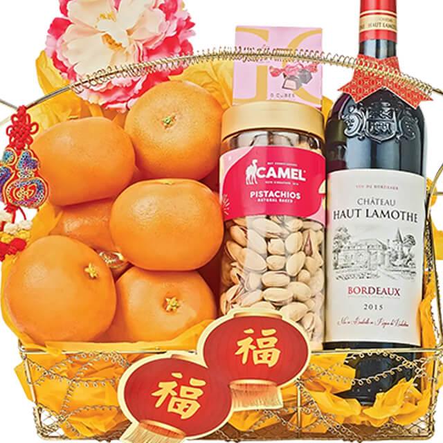 Chinese New Year gift hamper with fresh oranges, pistachios, wine, and festive flowers for delivery