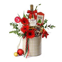 Christmas flower delivery basket with red gerbera, bottle of wine, pinecones, and festive decor