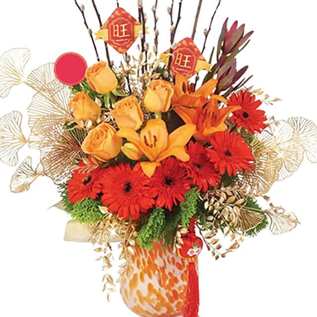 Vibrant orange and yellow fresh flower arrangement in a decorative vase for flower delivery