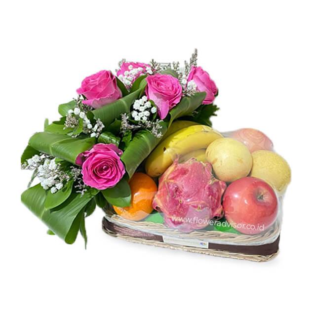 Flower delivery basket with pink roses, green foliage, and assorted fresh fruits