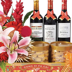 Festive flower arrangement with lilies, red flowers, wine bottles, and assorted gift jars for delivery