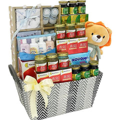 Gift hamper with wellness products, baby care items, plush lion toy, and flower delivery ribbon.